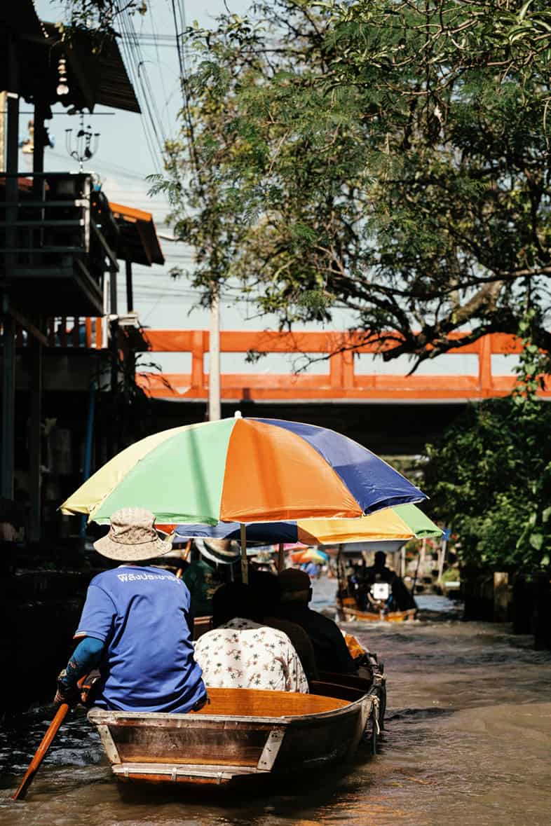 songkran festival - Why Thailand’s Songkran Festival Should Be on Your Travel Bucket List A boat rider in Thailand holding an umbrella.